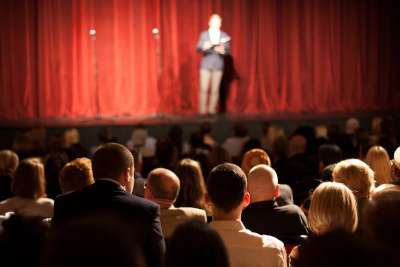 Comédien stand-up en train de se produire sur la scène d'un théâtre devant un public