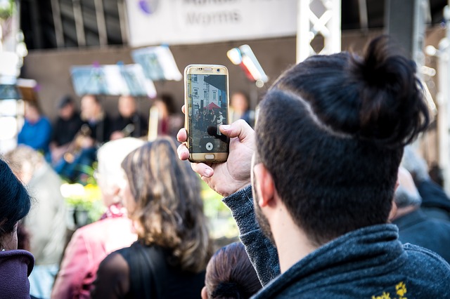 Jeune homme filmant avec son smartphone lors d'un événement