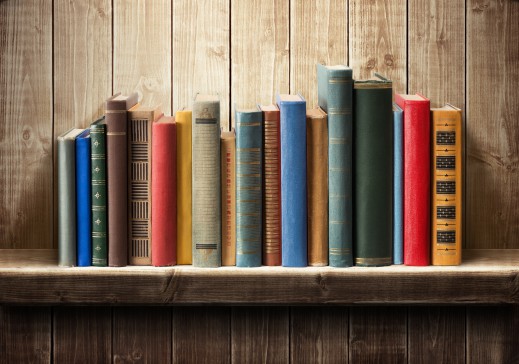 Books of different sizes, colors, and lengths sitting on a shelf