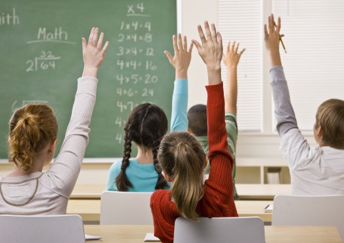 Children raising their hands in a math class.