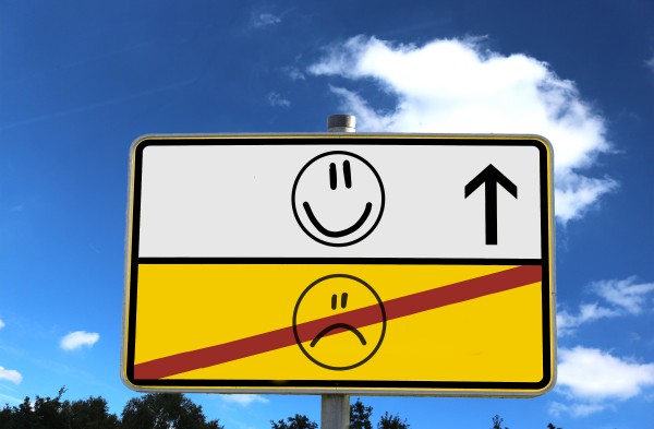 A road sign with a happy face and a sad face