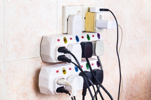 Multiple electricity plugs are plugged into an adapter.  This creates a risk of overload and is dangerous.