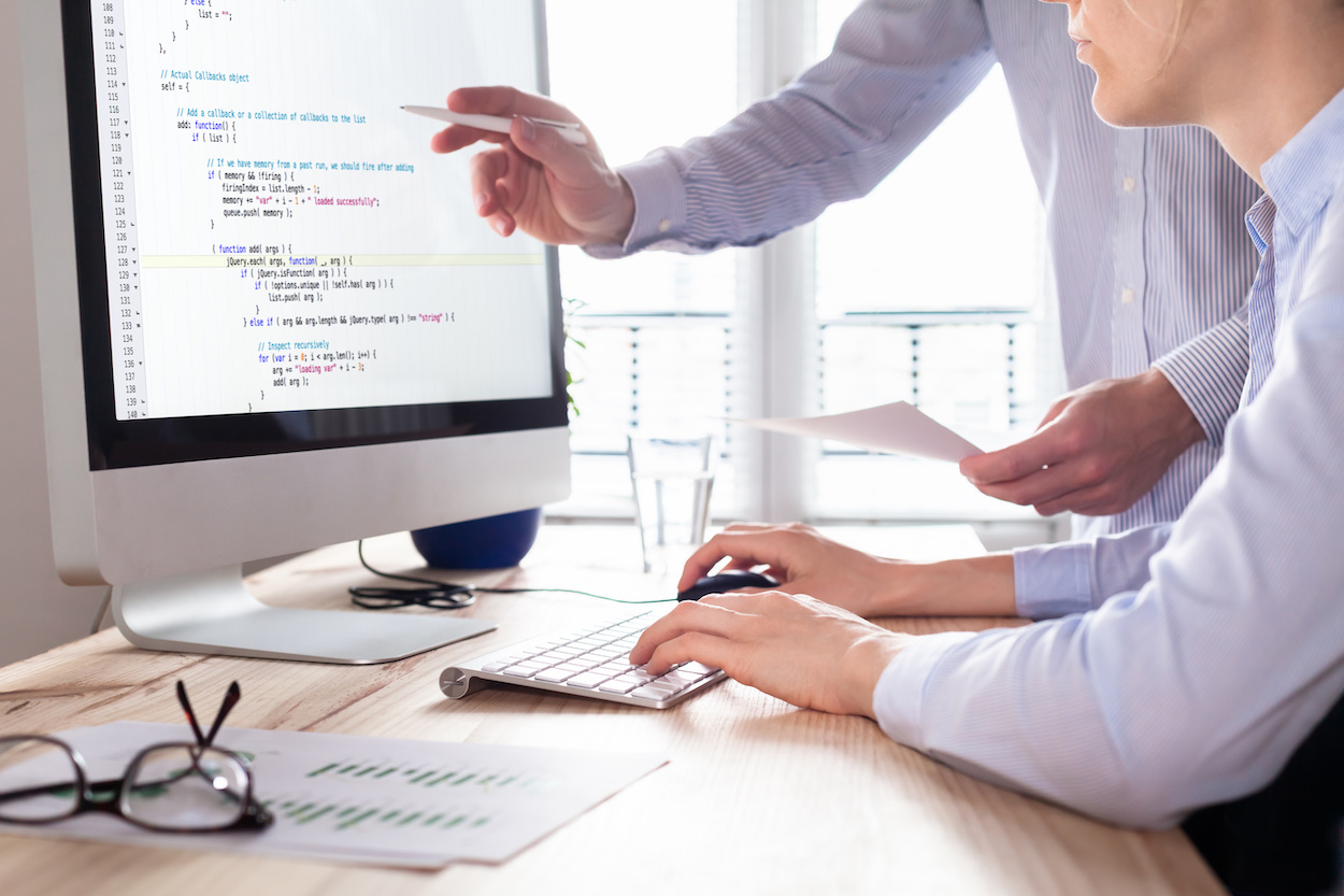 Photo d'une personne qui code et qui se fait aider par une autre