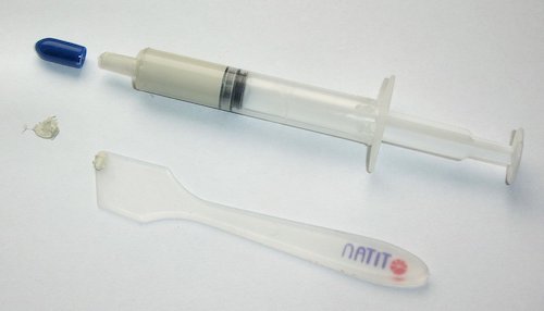 A syringe of thermal paste and spreader.