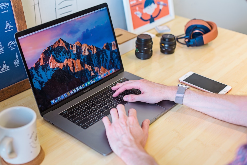 Deux mains masculines sur un Macbook Pro, prêtes à se lancer dans le travail !