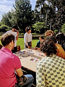 Photographie avec des personnes autour d'une table regardant des cartes posées dessus.