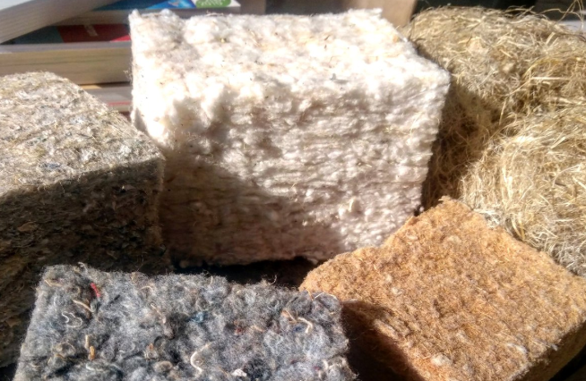 Blocs d’isolants écologiques de différentes textures et couleurs, fabriqués à partir de matériaux naturels comme la laine de mouton, le chanvre, la paille et le textile recyclé.