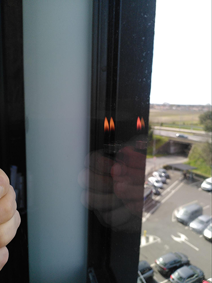 Photographie du reflet d'une flamme de briquet dans une vitre